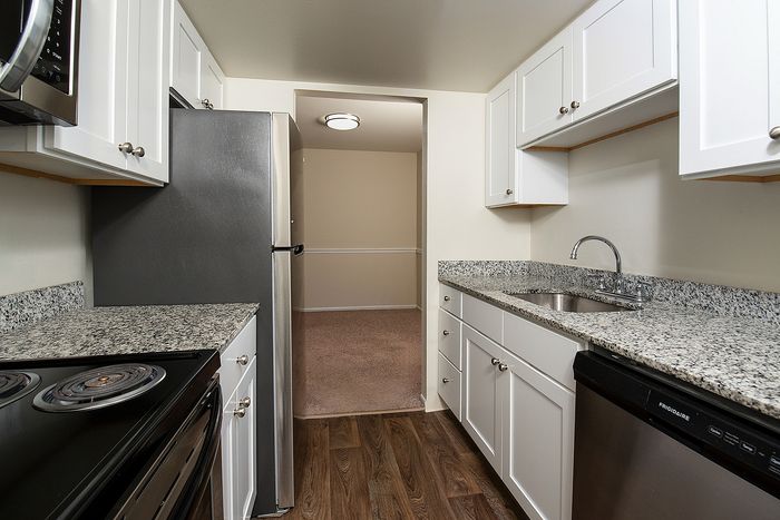 Modern kitchen with sleek granite countertops, stainless steel appliances, and elegant white cabinetry, offering a stylish and functional space.