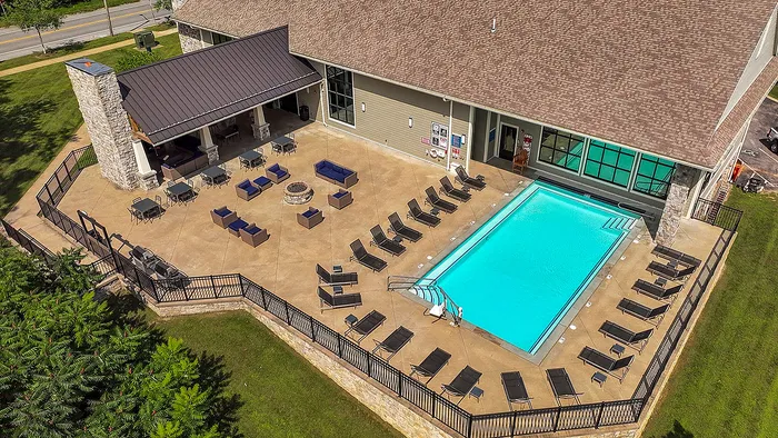 Luxurious apartment complex featuring a sparkling outdoor pool, relaxing lounge chairs, and elegant seating area, perfect for entertaining.