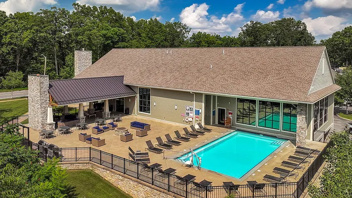 Stunning clubhouse with a modern outdoor patio, luxurious swimming pool, and sun loungers surrounded by lush greenery.