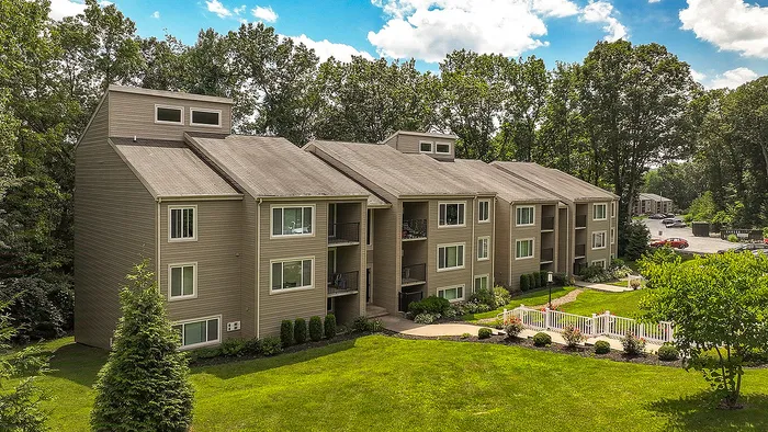 Charming apartment complex surrounded by lush greenery and bright blue skies, offering a serene and inviting living environment.