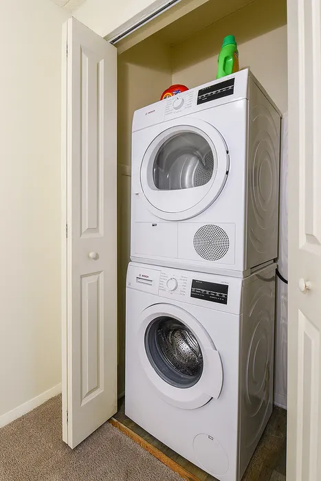 Compact laundry nook featuring a modern stacked washer and dryer set, perfectly integrated into a cozy closet space.