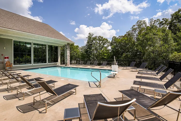 Inviting outdoor pool surrounded by modern lounge chairs, perfect for relaxation and soaking up the sun under a clear blue sky.