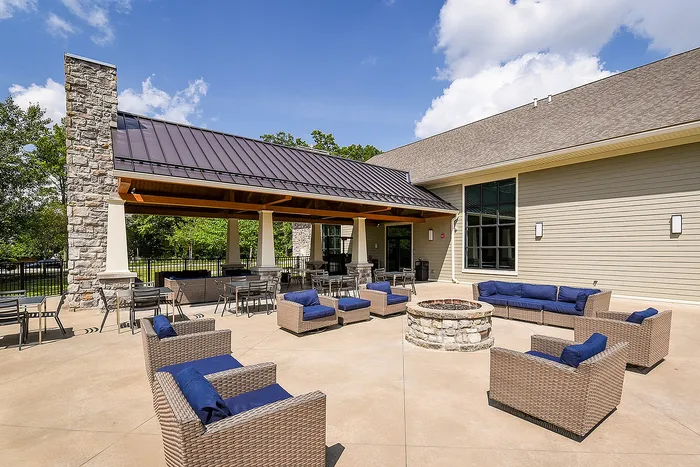 Inviting outdoor patio with comfortable wicker seating, stone fireplace, and covered dining area, perfect for social gatherings and relaxation.