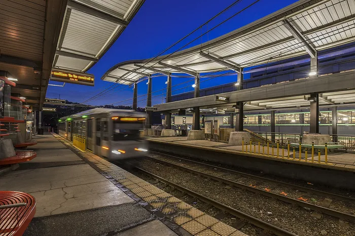 Vibrant urban transit station at dusk with a sleek modern train arriving, showcasing dynamic city living.