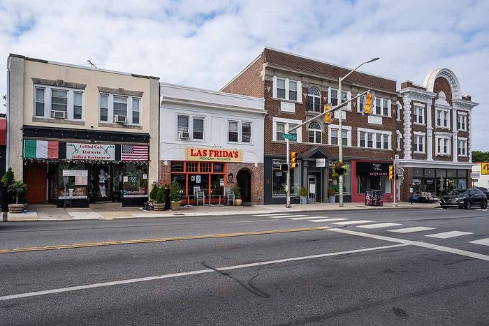Charming city street with diverse restaurants and boutique shops, showcasing vibrant community life in a historic building setting.