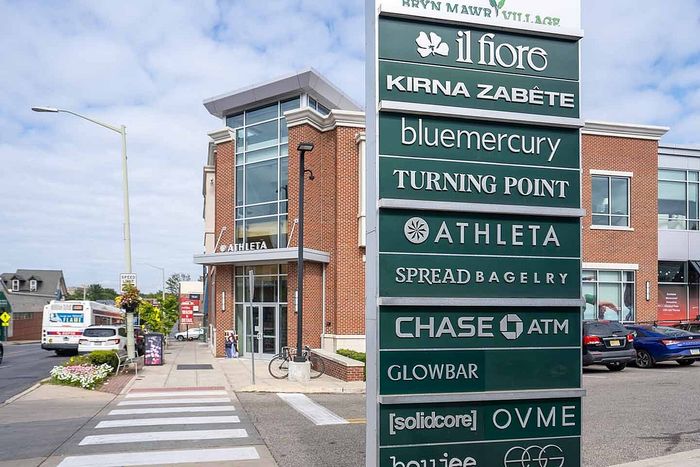 Modern shopping plaza featuring a variety of stores and services including Athleta, Chase ATM, and bagel shop, set against a backdrop of contemporary architecture.