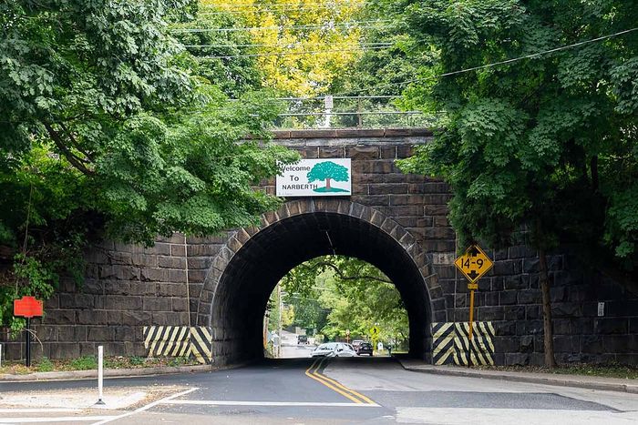 Quaint stone bridge with lush green trees, welcoming travelers to Narberth, offering a charming and scenic entryway.