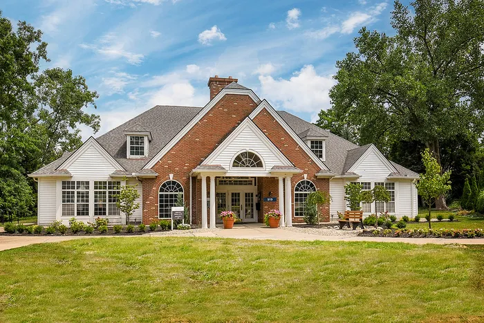 Charming brick and white wood building with a classic design, surrounded by lush greenery and vibrant floral accents.