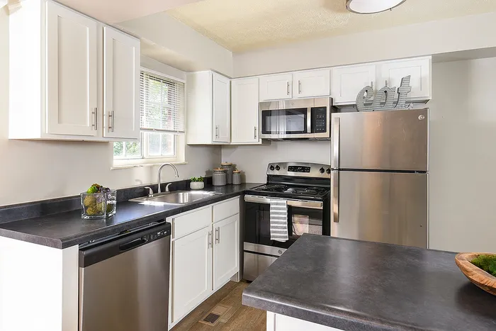 Apartments Near South Park - Heritage Hills - Kitchen With Stainless Steel Appliances, White Cabinets, And Kitchen Bar
