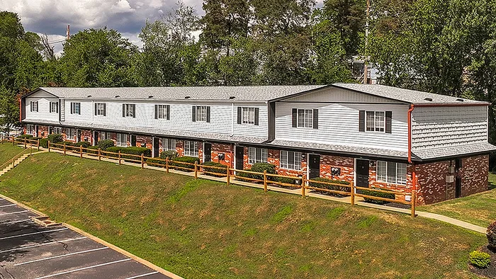 Charming townhouse complex surrounded by lush greenery with ample parking and vibrant exterior, perfect for family living.