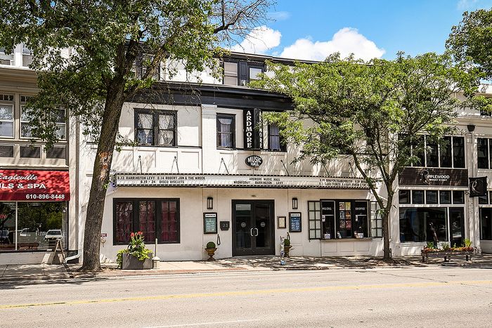 Charming street view of Ardmore Music Hall, nestled between lush trees and vibrant storefronts, perfect for entertainment enthusiasts.