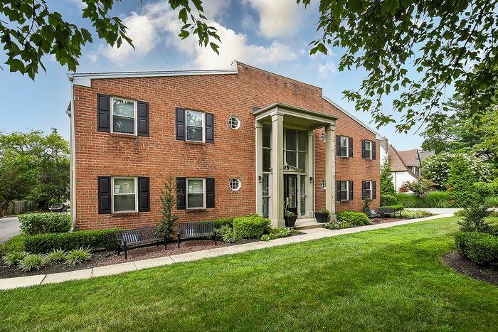 Charming brick apartment building with lush landscaping and inviting entrance, perfect for modern living.