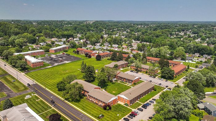 Scenic aerial view of a vibrant apartment community surrounded by lush greenery and peaceful suburban landscape.