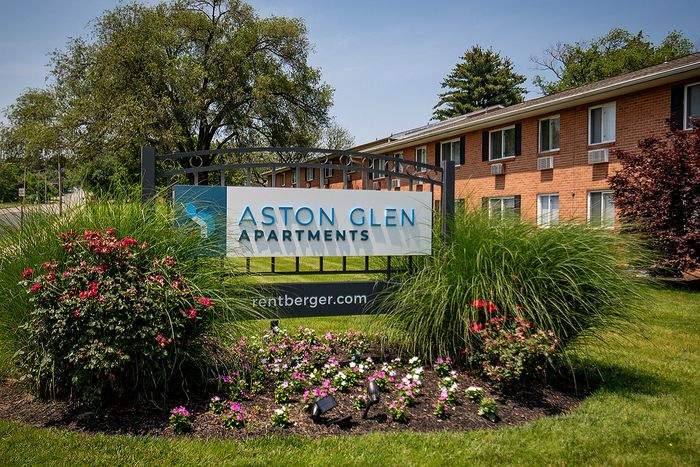 Charming entrance to Aston Glen Apartments featuring vibrant landscaping and inviting signage.