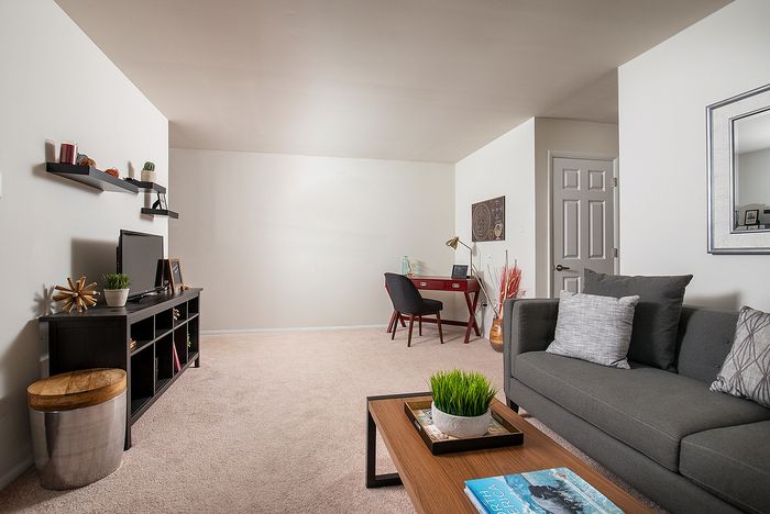 Modern living room with elegant gray sofa, stylish coffee table, and a cozy workspace featuring a minimalist desk and chair.