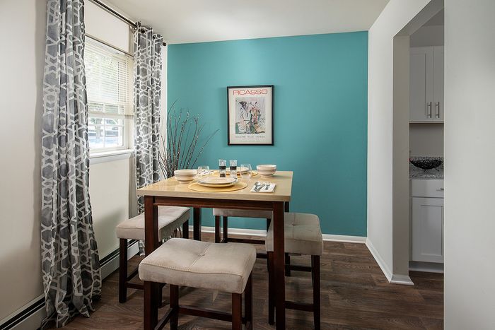 Modern dining area with a teal accent wall, elegant table setting, and stylish patterned curtains.