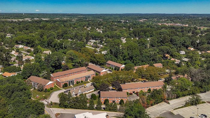 Charming aerial view of apartment complex nestled in lush greenery, offering a serene suburban lifestyle.