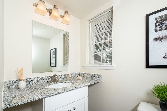 Elegant bathroom with granite countertop, modern lighting, and minimalist decor.