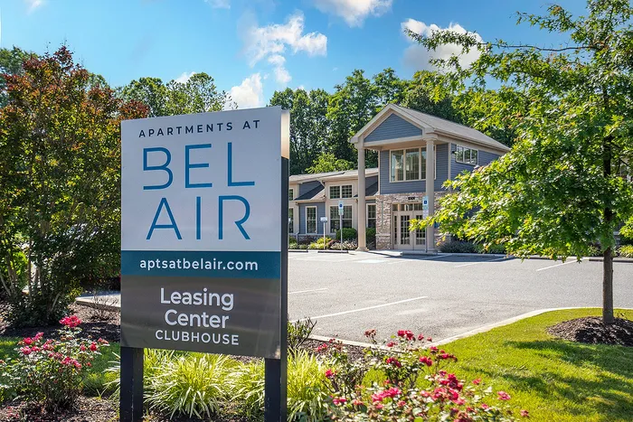 Inviting leasing center at Bel Air Apartments with lush landscaping and bright, modern architecture under a clear blue sky.