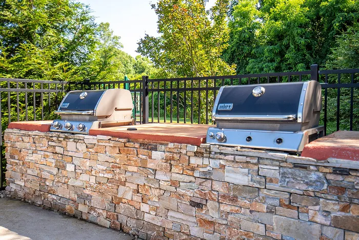 Inviting outdoor entertainment area featuring premium stone brick BBQ grills surrounded by lush greenery.
