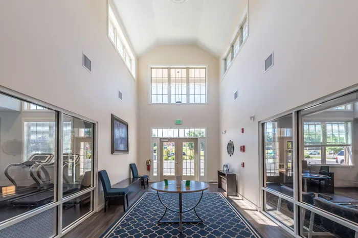 Inviting apartment lobby with high ceilings, large windows, and natural light enhancing elegant decor.