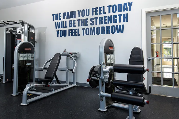 Modern gym with state-of-the-art exercise equipment and motivational wall quote emphasizing strength and fitness.