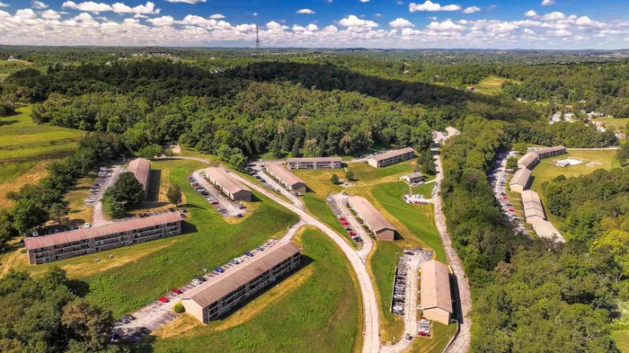 Scenic aerial view showcasing hillside apartment complex surrounded by lush greenery and open spaces.