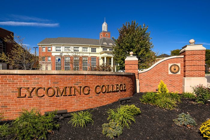 Lycoming College entrance with elegant brick architecture and lush landscaping under a clear blue sky.