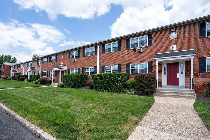 Charming brick apartment complex with manicured lawns and inviting entrances, ideal for comfortable living.