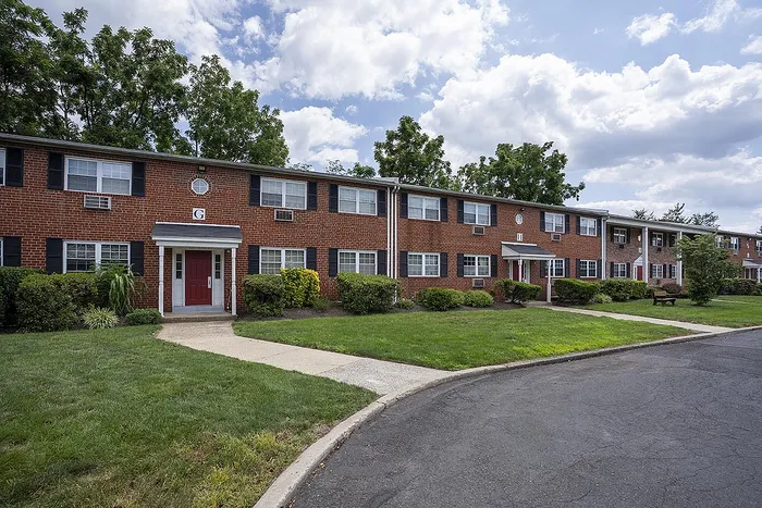 Charming brick apartment complex with lush green lawns and inviting walkways, perfect for comfortable living.