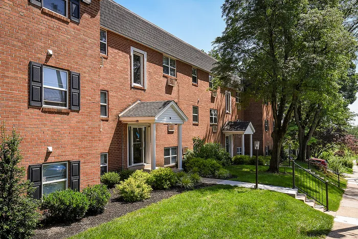 Charming brick apartment exterior with lush greenery and inviting entrance, perfect for modern urban living.