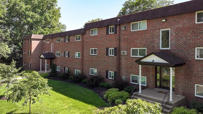 Charming brick apartment complex surrounded by lush greenery, showcasing a serene residential setting.