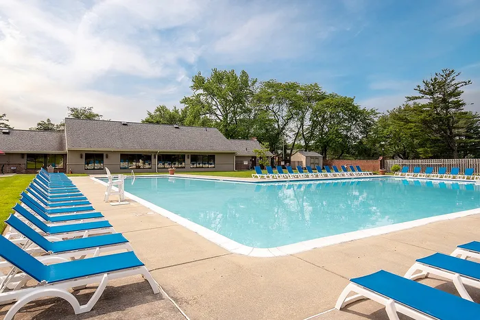 Inviting outdoor pool area with vibrant blue loungers, perfect for relaxation under the sunny sky.