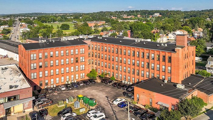 Charming red-brick apartment building with modern amenities and ample parking, set in a lush, green neighborhood.