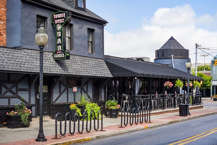 Charming bar and grill with outdoor seating, vibrant floral displays, and inviting ambiance.