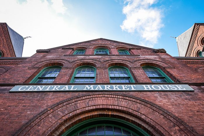 Charming brick facade of the historic Central Market House with arched windows and a bright blue sky backdrop.
