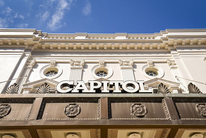 Elegant architectural facade of the Capitol building featuring intricate columns and classic detailing under a bright blue sky.
