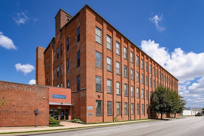 Charming red brick apartment building under a clear blue sky, offering urban living with historical elegance.