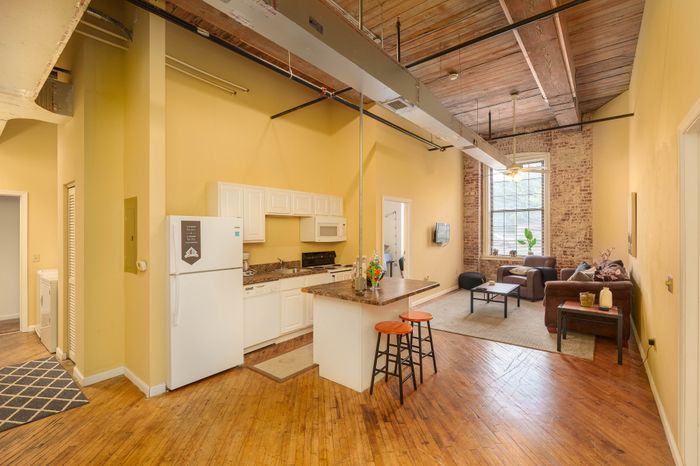 Charming loft apartment with open-concept kitchen, cozy living area, and rustic brick accents.