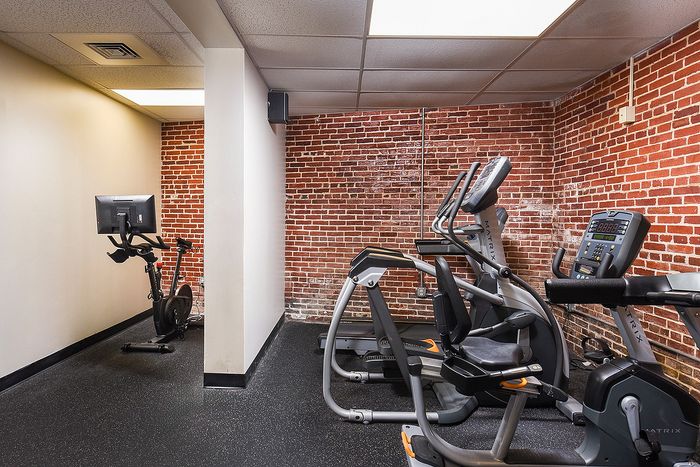 Chic fitness room featuring modern exercise equipment, exposed brick walls, and ample lighting for an invigorating workout experience.