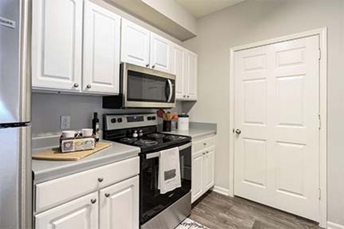 Bright modern kitchen with stainless steel appliances, sleek countertops, and classic white cabinetry.