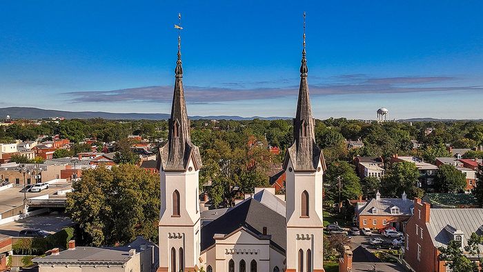 Elegant aerial view showcasing a charming cityscape with a historic church and lush greenery, set against a clear blue sky.