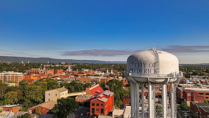 Charming aerial view of Frederick cityscape with iconic water tower and vibrant architecture under clear blue skies.