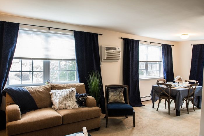 Inviting living and dining area with elegant navy curtains, cozy brown sofa, and stylish dining table set for a memorable gathering.