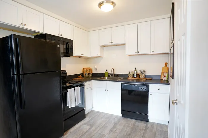 Contemporary kitchen boasting sleek black appliances, elegant white cabinetry, and a cozy atmosphere for culinary delights.