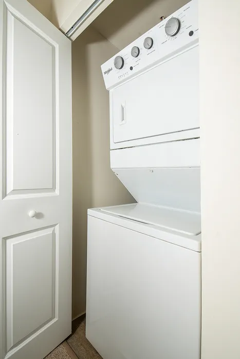 Convenient in-unit laundry with a sleek stackable washer and dryer tucked behind a white door, perfect for easy home living.