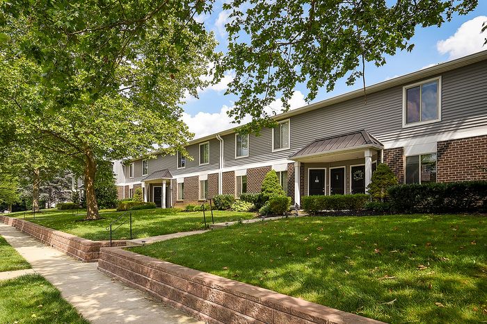 Charming townhouse exterior with lush green landscaping, inviting pathway, and modern architectural details.