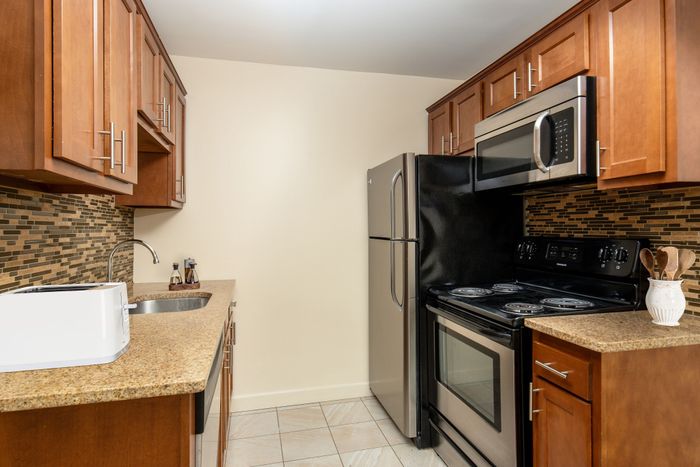 Modern kitchen with sleek stainless steel appliances, granite countertops, and elegant cherry wood cabinets.