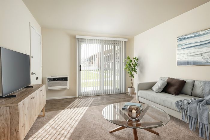 Bright and inviting living room with modern decor, showcasing a stylish glass coffee table, cozy gray sofa, and a large window with natural light streaming in, complemented by a touch of greenery.