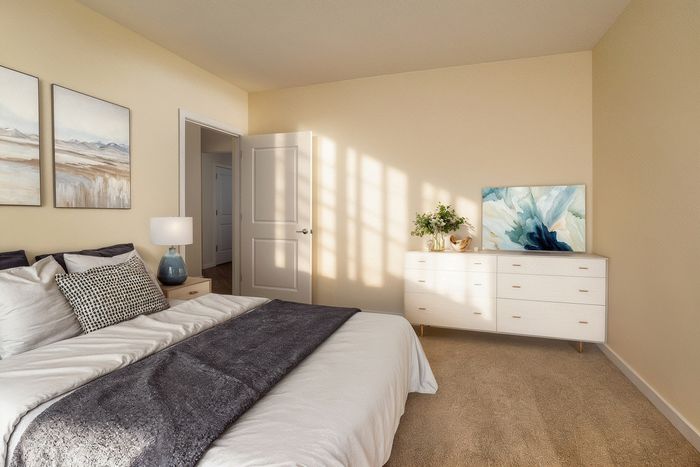 Cozy and inviting bedroom with soft lighting, featuring modern decor, a comfortable bed, and stylish artwork adorning the cream-colored walls.